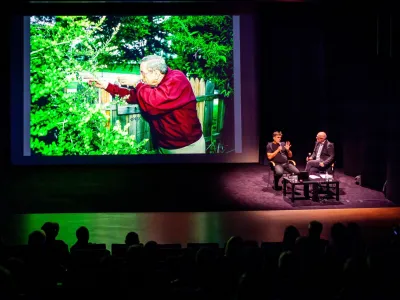 Ed Hoffman pred objektivom Arneta Hodaliča simulira, kako je videl drugega strelca. V desnem kotu v Linhartovi dvorani sta se o znameniti fotoreportaži pogovarjala Arne Hodalič (levo) in Ali Žerdin (desno).