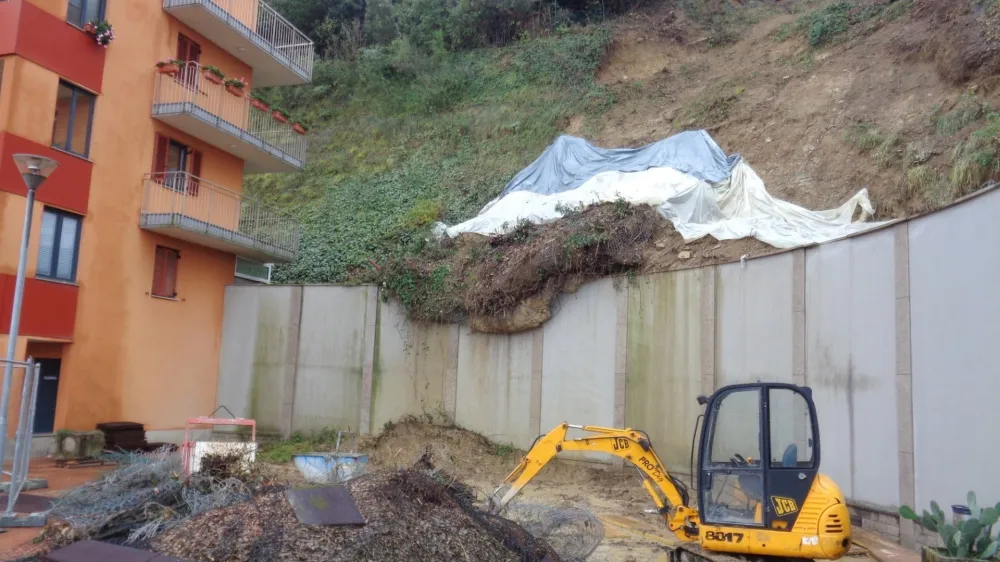 Delavci odstranjujejo približno 25 metrov dolgo plazino in utrjujejo brežino ob bloku.&nbsp;