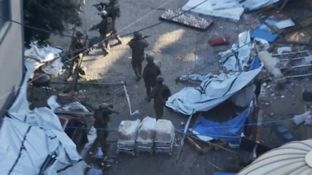 In this image taken from a video released by the Israeli Defense Forces on Tuesday, Nov. 15, 2023, Israeli soldiers walk in the area of Al-Shifa hospital in Gaza City. The Israeli military released footage on Tuesday that it said shows joint operational activity of two army brigades in its advancement on the ground in Gaza Strip. (Israel Defense Forces via AP)