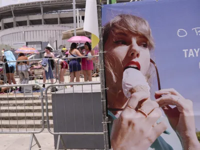 Taylor Swift fans wait for the doors of Nilton Santos Olympic stadium to open for her Eras Tour concert amid a heat wave in Rio de Janeiro, Brazil, Saturday, Nov. 18, 2023. A 23-year-old Taylor Swift fan died at the singer's Eras Tour concert in Rio de Janeiro Friday night, according to a statement from the show's organizers in Brazil. (AP Photo/Silvia Izquierdo)