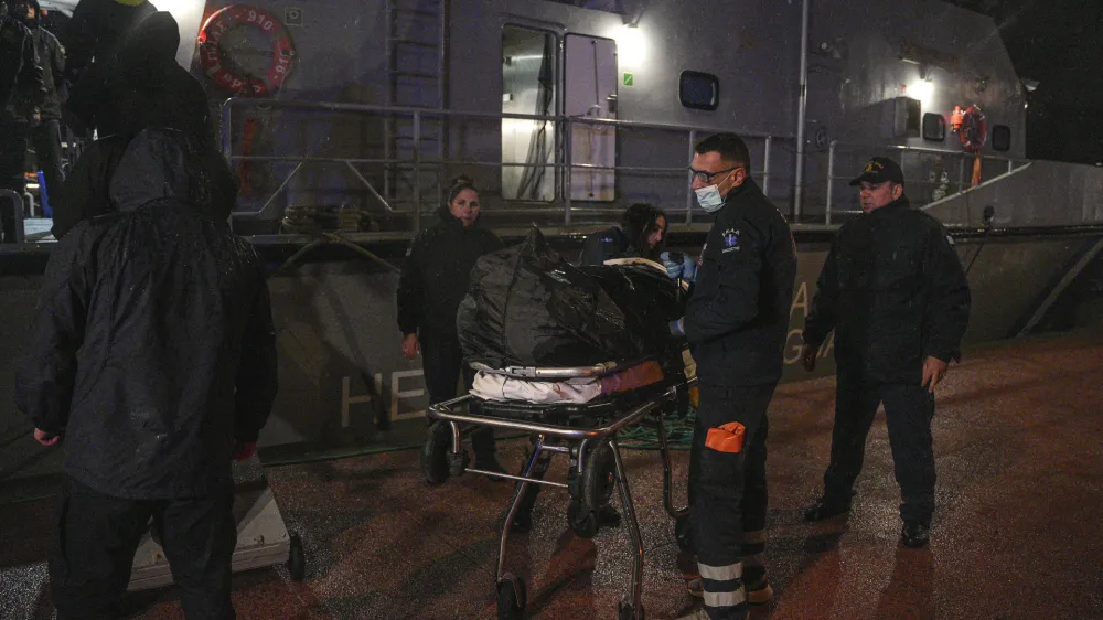 Paramedics carry the body of a crew member of a ship, on the northeastern Aegean Sea island of Lesbos, Greece, Sunday, Nov. 26, 2023. A cargo ship sank off the Greek island of Lesbos early Sunday, leaving 13 crew members missing and one rescued, authorities said. The Raptor, registered in the Comoros, was on its way to Istanbul from Alexandria, Egypt, carrying 6,000 tons of salt, the coast guard said. It had a crew of 14, including eight Egyptians, four Indians and two Syrians, the coast guard said.(AP Photo/Panagiotis Balaskas)