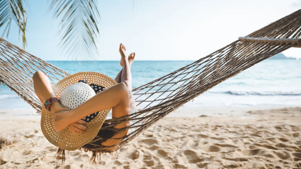 Summer travel vacation concept, Happy traveler asian woman with white bikini relax in hammock on beach in Koh mak, Thailand