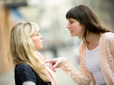 Two women talking to each other and arguing.