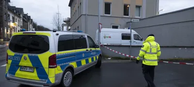 03 January 2024, North Rhine-Westphalia, Finnentrop: A police man stands next to a police vichel near the Lennepark, following the violent death of a 72-year-old man in Finnentrop. A 19-year-old has handed himself in to the police. Photo: Kai Osthoff/dpa