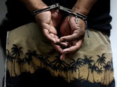 A handcuffed detainee is shown at a police station in the aftermath of a wave of violence that saw the storming of a TV station on-air and explosions around the nation, in Guayaquil, Ecuador, January 11, 2024. REUTERS/Ivan Alvarado