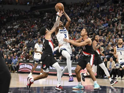 Minnesota Timberwolves forward Jaden McDaniels (3) drives to the basket between Portland Trail Blazers guard Anfernee Simons, left, and guard Malcolm Brogdon (11) during the second half of an NBA basketball game Friday, Jan. 12, 2024, in Minneapolis. (AP Photo/Craig Lassig)
