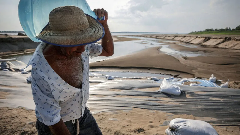 FILE PHOTO: A man carries a water jug during a historic drought in the Amazon at the dry riverbed of the Paraua river in Careiro da Varzea, Amazonas state, Brazil October 26, 2023.    REUTERS/Bruno Kelly/File Photo
