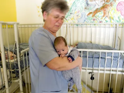 A nurse holds a baby at a center for nutritional recuperation in Timisoara, Romania, 600 kilometers (373 miles) west of Bucharest, Wednesday May 10, 2006. The center, which houses 59 children of which 12 are registered as abandoned is mentioned in a report by an advocacy organization charging Wednesday that Romania warehouses mentally ill children in adult institutions in filthy and degrading conditions. Romanian officials on Wednesday acknowledged problems in caring for disabled and abandoned children, but disputed allegations by a U.S. human rights group of widespread neglect and abuse. (AP Photo/Vadim Ghirda) ROMANIA OUT