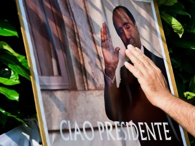 A person touches a placard as people pay their respects outside former Italian Prime Minister Silvio Berlusconi's house, to which his body was transported following his death, in Arcore near Milan, Italy, June 12, 2023. REUTERS/Massimo Pinca