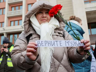 The wife of a mobilised serviceman, who joined the Russian armed forces involved in a military campaign in Ukraine, comes together with members of the women's movement "Way Home" to lay flowers at the Tomb of the Unknown Soldier by the Kremlin wall and to demand return of their husbands from Ukraine front, in Moscow, Russia, February 3, 2024. A slogan on the ribbon reads: "Bring husband back". REUTERS/Stringer