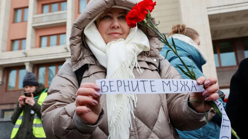 The wife of a mobilised serviceman, who joined the Russian armed forces involved in a military campaign in Ukraine, comes together with members of the women's movement "Way Home" to lay flowers at the Tomb of the Unknown Soldier by the Kremlin wall and to demand return of their husbands from Ukraine front, in Moscow, Russia, February 3, 2024. A slogan on the ribbon reads: "Bring husband back". REUTERS/Stringer