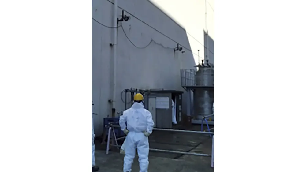In this photo provided by Tokyo Electric Power Company Holdings, Inc. (TEPCO), a staff member examines an air vent through which a plant worker found the leak Wednesday morning, at the crippled Fukushima Daiichi nuclear power plant in Okuma town, northeastern Japan, Wednesday, Feb. 7, 2024. Highly radioactive water leaked from a treatment machine at the tsunami-hit Fukushima nuclear power plant, but no one was injured and radiation monitoring shows no impact to the outside environment, the utility operator said Thursday. (TEPCO via AP)