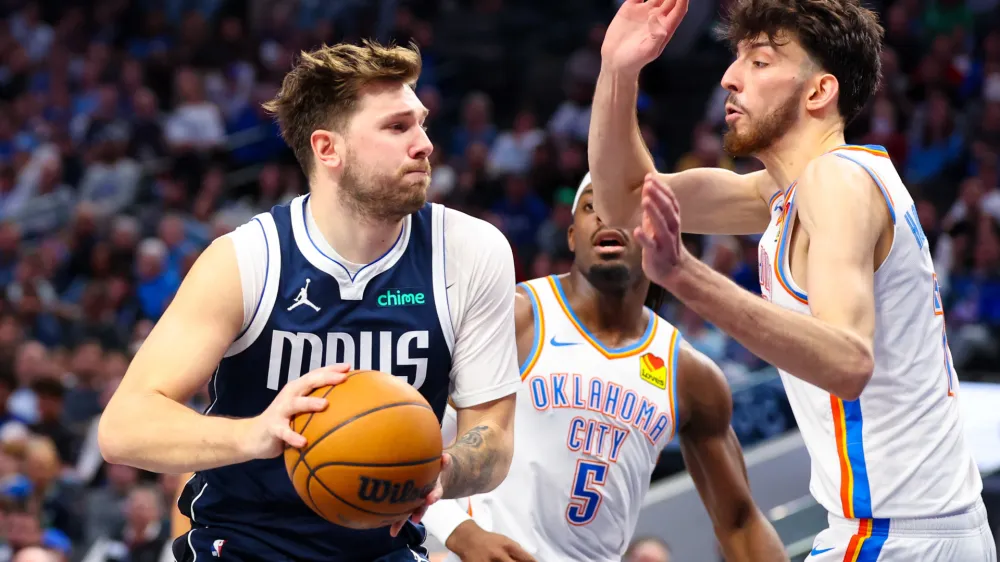 Feb 10, 2024; Dallas, Texas, USA; Dallas Mavericks guard Luka Doncic (77) drives to the basket as Oklahoma City Thunder forward Chet Holmgren (7) and Oklahoma City Thunder guard Luguentz Dort (5) defend during the second half at American Airlines Center. Mandatory Credit: Kevin Jairaj-USA TODAY Sports