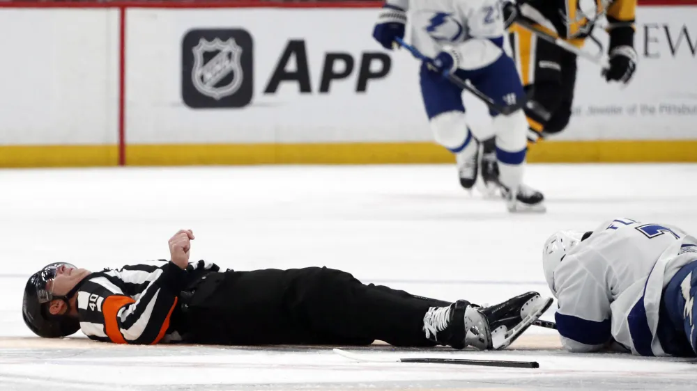 Apr 6, 2024; Pittsburgh, Pennsylvania, USA; NHL referee Steve Kozari (40) lays on the ice after an accidental collision with Tampa Bay Lightning defenseman Haydn Fleury (7) during the third period of the game against the Pittsburgh Penguins at PPG Paints Arena. The Penguins won 5-4. Mandatory Credit: Charles LeClaire-USA TODAY Sports
