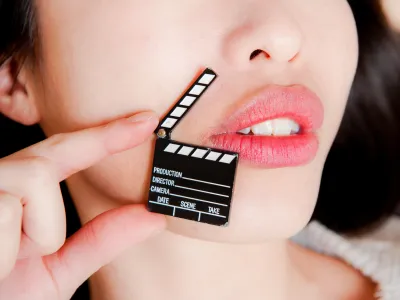 Face detail of sensual woman lips, no eyes, with hand holding little movie clapper board