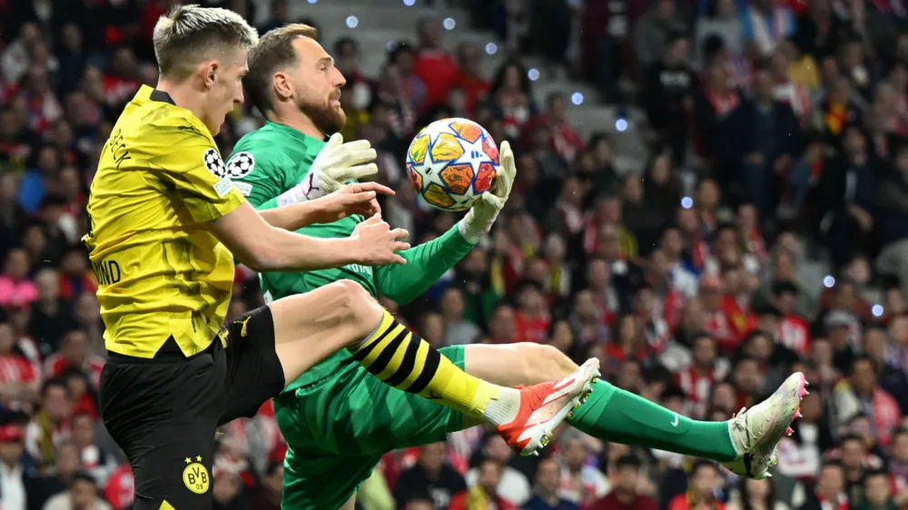 10 April 2024, Spain, Madrid: Madrid goalkeeper Jan Oblak (R) and Dortmund's Nico Schlotterbeck fight for the ball during the UEFA Champions League quarter-finals first leg soccer match between Atletico Madrid and Borussia Dortmund at Wanda Metropolitano. Photo: Federico Gambarini/dpa