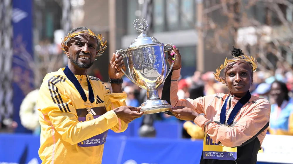 Apr 15, 2024; Boston, MA, USA; Sisay Lemma of Ethiopia and Hellen Obiri of Kenya pose at the finish line with the winners trophy at the 2024 Boston Marathon. Mandatory Credit: Eric Canha-USA TODAY Sports