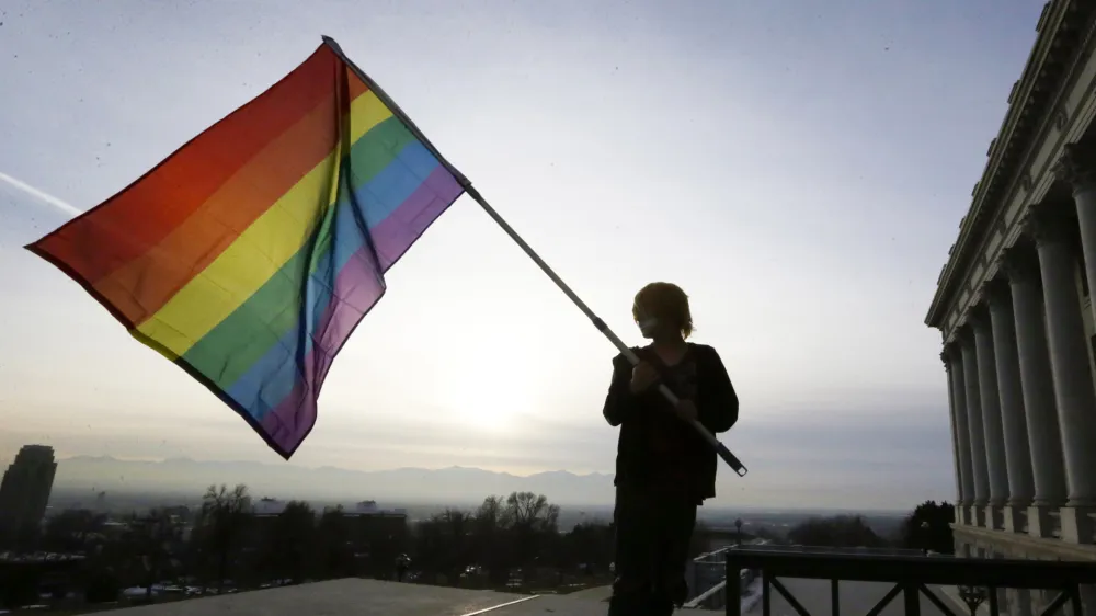 FILE - Corbin Aoyagi, a supporter of gay marriage, waves a rainbow flag during a rally at the Utah State Capitol on Jan. 28, 2014, in Salt Lake City. Utah teachers will be free to display LGBTQ+ pride flags and other social, political or religious imagery after the state House blocked a bill Monday, Feb. 26, 2024, that would have banned teachers from using their position to promote or disparage certain beliefs. (AP Photo/Rick Bowmer, File)