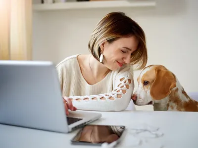 Caucasian businesswoman playing with dog in home office