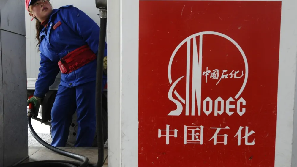 An attendant fills the tank of a vehicle at a Sinopec gas station in Changzhi, Shanxi province March 28, 2010. Sinopec, Asia's top oil refiner, will buy a stake in upstream assets in Angola for $2.46 billion and said it wanted more such deals, which could shield it from high oil prices that hit margins in the fourth quarter. Picture taken March 28, 2010.  REUTERS/Stringer (CHINA - Tags: ENERGY BUSINESS) CHINA OUT. NO COMMERCIAL OR EDITORIAL SALES IN CHINA