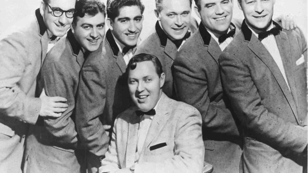Bill Haley (sedeč v sredini) &amp; his Comets so Rock around the clock posneli leta 1954, prva rock'n'roll skladba, ki je zasedla vrh lestvice v ZDA in po svetu, pa je postala leto kasneje.