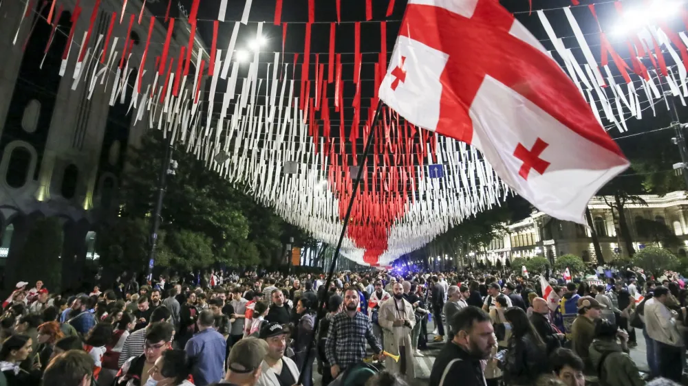 Demonstrators with a Georgian national flag gather at the Parliamentary building during an opposition protest against the foreign influence bill in Tbilisi, Georgia, Tuesday, May 28, 2024. The Georgian parliament has overridden a presidential veto of the "foreign agents" legislation that has fueled Western concerns and sparked massive protests for weeks. (AP Photo/Zurab Tsertsvadze)
