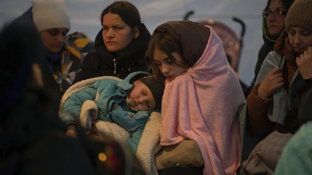 Refugees, mostly women with children, rest inside a tent after arriving at the border crossing, in Medyka, Poland on Sunday, March 6, 2022. (AP Photo/Visar Kryeziu)