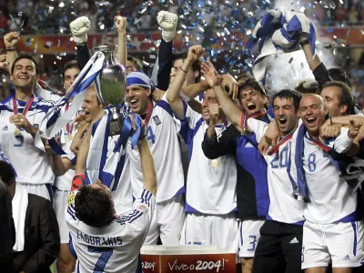 Greece players led by captain Theodoros Zagorakis (7) celebrate on the podium with the cup after winning the Euro 2004 soccer final in Lisbon July 4, 2004. Greece defeated host Portugal 1-0. REUTERS/Mike Finn-Kelcey GB/KC - RTRT6LD
