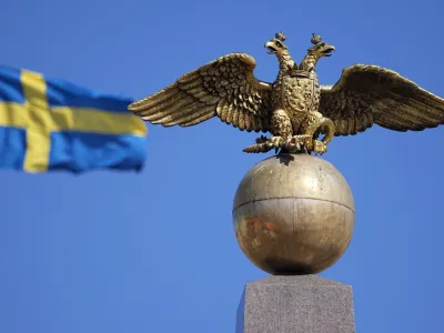 A Russian Imperial double-headed eagle is seen in front of a Sweden flag on the Czarina's Stone in the Market Square, in Helsinki, Finland, Friday, May 13, 2022. Finnish leaders announced Thursday their belief that Finland should join the world's biggest military organization because of Russia's war in Ukraine. Sweden could soon follow suit. (AP Photo/Martin Meissner)
