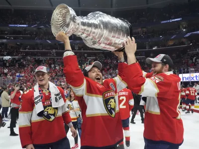 Florida Panthers defenseman Brandon Montour, center, lifts the Stanley Cup trophy after Game 7 of the NHL hockey Stanley Cup Final against the Edmonton Oilers, Monday, June 24, 2024, in Sunrise, Fla. The Panthers defeated the Oilers 2-1. (AP Photo/Wilfredo Lee)