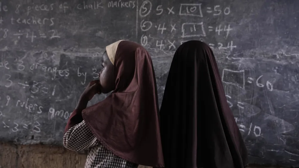 Students of Excellent Moral School attempt to answer a mathematics question on a blackboard inside a dimly lit classroom in Ibadan, Nigeria, Tuesday, May 28, 2024. Schools like Excellent Moral operate in darkness due to zero grid access, depriving students of essential tools like computers. (AP Photo/Sunday Alamba)
