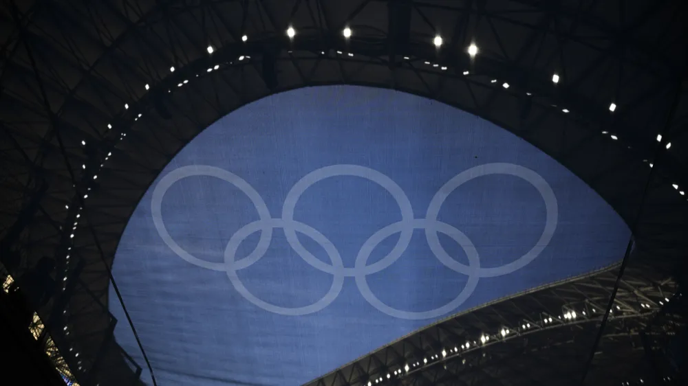 The Olympic rings are pictured through a flag hanging in the Velodrome stadium before the start of the men's Group A soccer match between France and the United States during the 2024 Summer Olympics, Wednesday, July 24, 2024, in Marseille, France. (AP Photo/Daniel Cole)