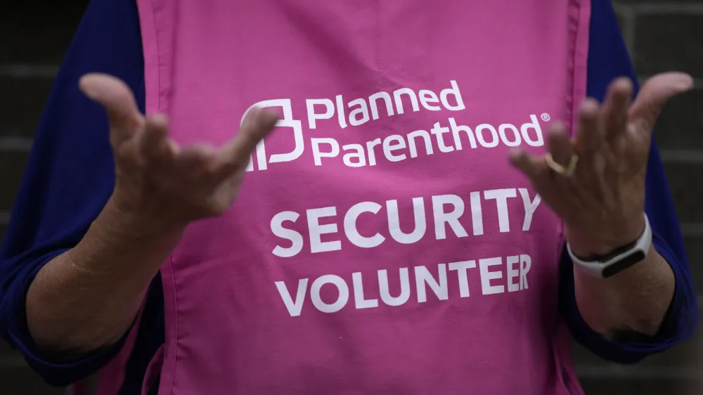 A Planned Parenthood clinic patient escort stands outside the building Thursday, July 18, 2024, in Ames, Iowa. (AP Photo/Charlie Neibergall)