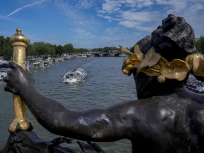 A tourist boat makes its way along the Seine River by the Alexandre III bridge, at the 2024 Summer Olympics, Sunday, July 28, 2024, in Paris, France. (AP Photo/Yasin Dar)