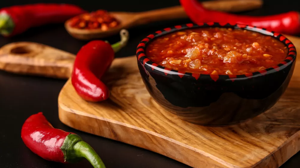 Traditional Maghrebi hot chili pepper sauce paste harissa on dark background, Tunisia and Arabic cuisine, horizontal orientation, closeup / Foto: Angelika Mostova