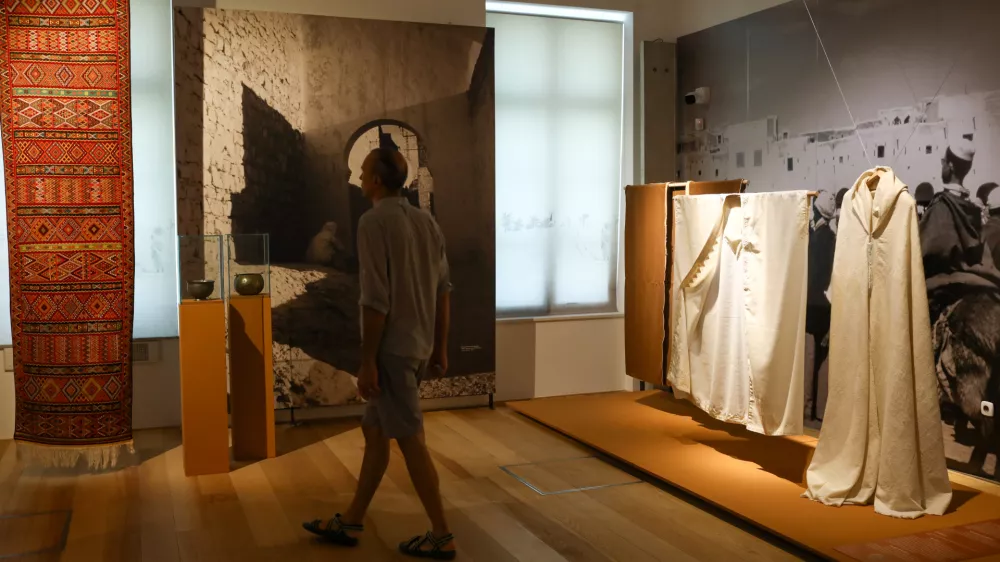 Odsev tradicionalnega oblačenja v severni Afriki odražajo razstavljeni kosi oblačil, med njimi je redek bel burnus s kapuco izvrstne kakovosti. Je ročno tkan iz grobe kamelje volne in okra&scaron;en z vezenino okrog vratu. Burnusi so lahko bele ali rjave barve. Foto Luka Cjuha