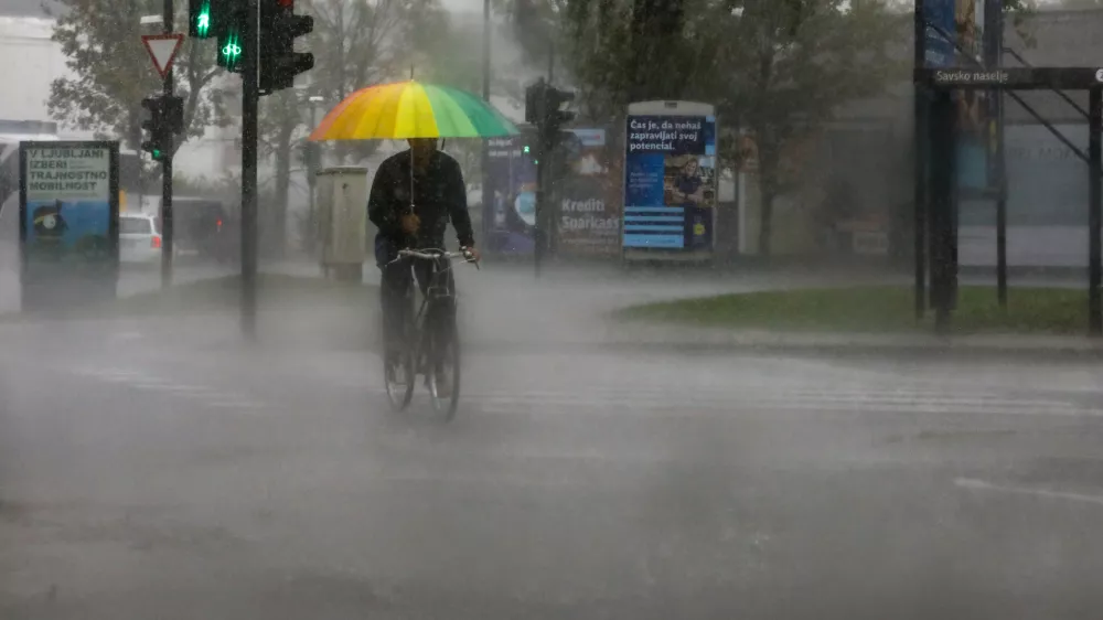 kolesar in dežnik- 15.09.2022 - Močno deževje in poplave v Ljubljani - neurje - meteorna voda je zalila več garaž, podhodov, kletnih in stanovanjskih prostorov, skladi&scaron;č in poslovnih prostorov, pa tudi prostore osnovne &scaron;ole in vrtca, lekarne ter Narodno galerijo.Foto: Luka Cjuha