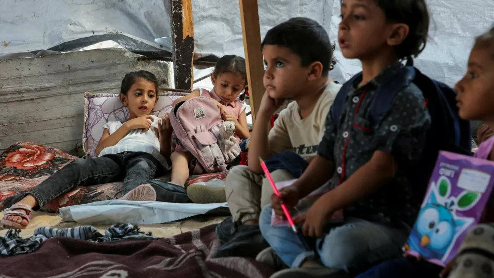 Palestinian students attend a class in a tent set up on the rubble of the house of teacher Israa Abu Mustafa, as war disrupts a new school year, amid the Israel-Hamas conflict, in Khan Younis, in the southern Gaza Strip, September 4, 2024. REUTERS/Hatem Khaled   TPX IMAGES OF THE DAY