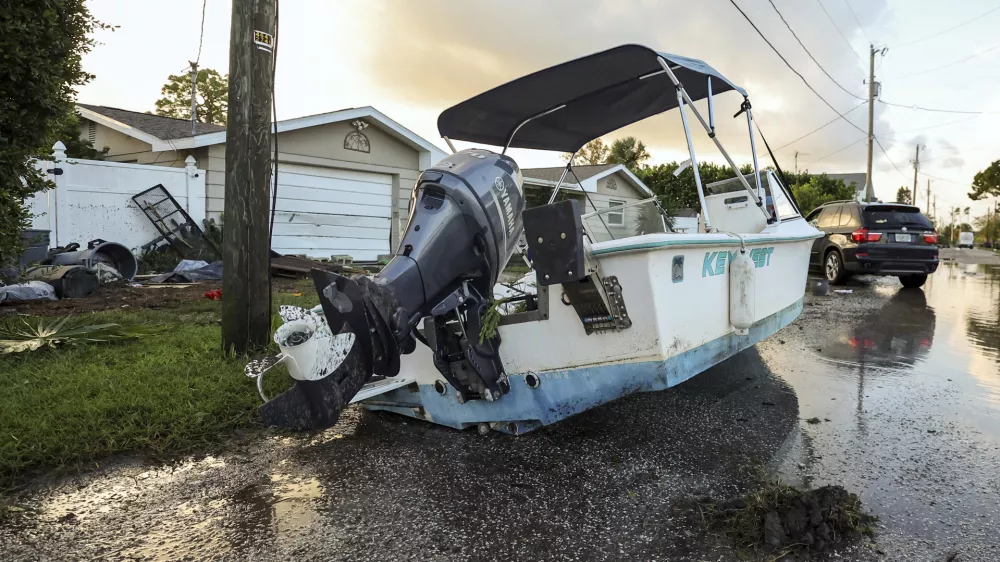 A boat rests on a street after being relocated during flooding caused by Hurricane Helene Friday, Sept. 27, 2024, in Hudson, Fla. (AP Photo/Mike Carlson)