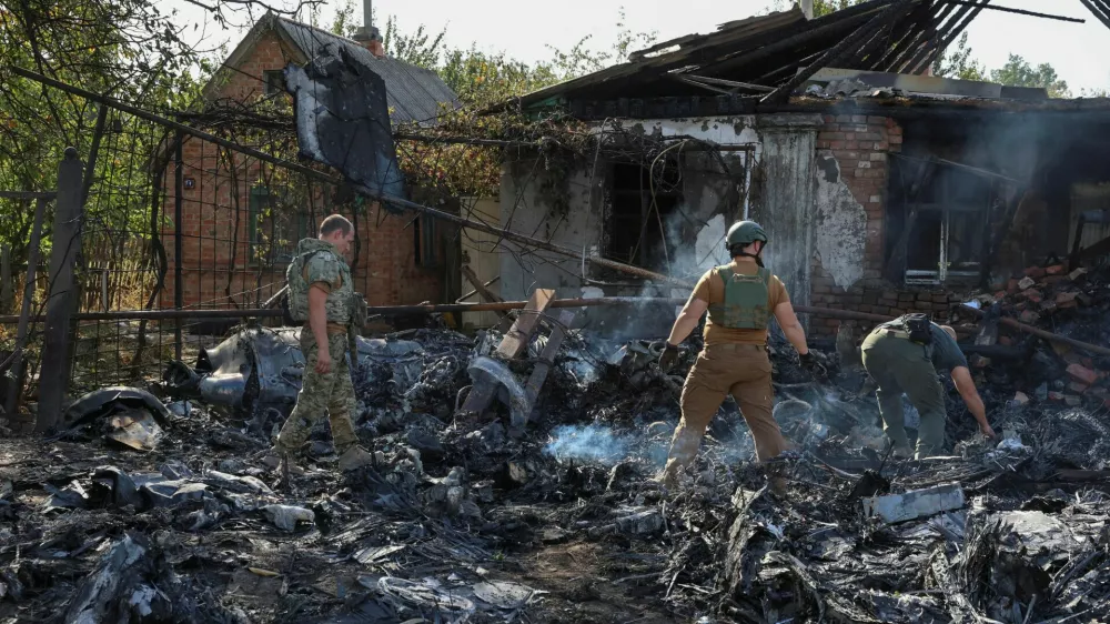 Ukrainian service members inspect parts of a Russian aerial vehicle, which local authorities assume to be a newest heavy unmanned aerial vehicle S-70 Okhotnik (Hunter) or variation of Sukhoi fighting jet, is seen in residential area of the town of Kostintynivka after it was shot down, amid Russia's attack on Ukraine, in Donetsk region, Ukraine October 5, 2024. Radio Free Europe/Radio Liberty/Serhii Nuzhnenko via REUTERS  THIS IMAGE HAS BEEN SUPPLIED BY A THIRD PARTY