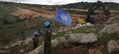 FILE - UN peacekeepers hold their flag, as they observe Israeli excavators attempt to destroy tunnels built by Hezbollah, near the southern Lebanese-Israeli border village of Mays al-Jabal, Lebanon, Dec. 13, 2019. (AP Photo/Hussein Malla, File)