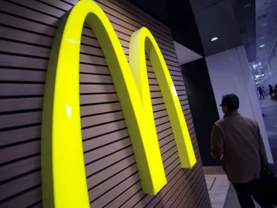 FILE - In this Dec. 17, 2014 file photo, a man walks by a McDonald's logo in front of its restaurant in Tokyo. McDonald's is set to unveil its latest plans to revive its sputtering business on Monday, May 4, 2015. (AP Photo/Eugene Hoshiko, File)