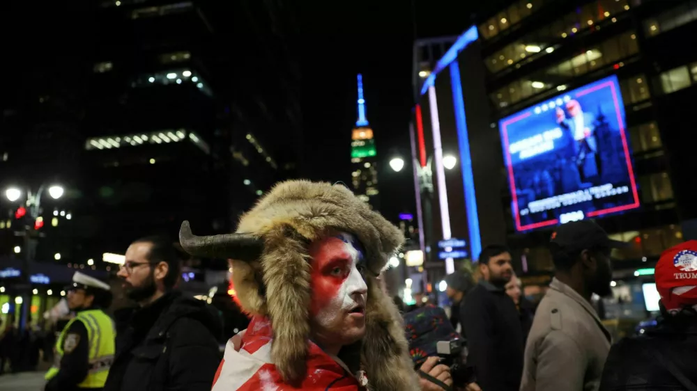A person dressed as the "QAnon Shaman" looks on as pedestrians walk past outside of Madison Square Garden during a rally for Republican presidential nominee and former U.S. President Donald Trump in New York City, U.S., October 27, 2024. REUTERS/Leah Millis