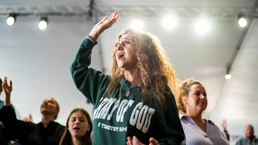 A member of Pastor Greg Locke's Global Vision Bible Church raises her hand during worship service in Mount Juliet, Tennessee, U.S. October 27, 2024. REUTERS/Seth Herald   TPX IMAGES OF THE DAY