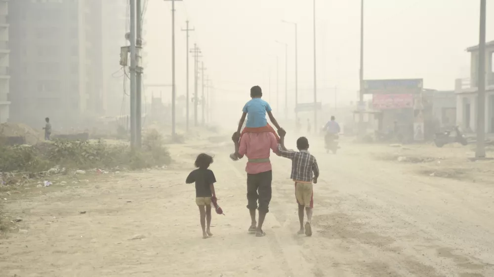 A village man walks carrying a child on his shoulders on a foggy day in Greater Noida, near New Delhi, India, Monday, Nov.5, 2018. With air quality reduced to "very severe" in the Indian capital region, authorities are bracing for a major Hindu festival featuring massive fireworks that threatens to cloak New Delhi with more toxic smog and dust. (AP Photo/R S Iyer)