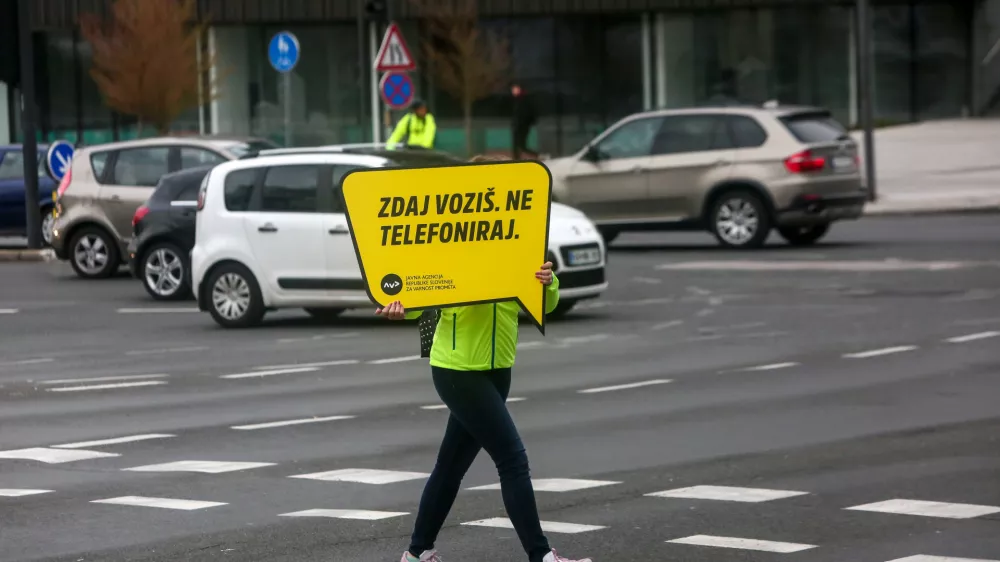 križi&scaron;če &Scaron;martinska cesta - Topni&scaron;ka ulica, opozorilna tabla ZDAJ VOZI&Scaron; NE TELEFONIRAJ- 27.03.2019 - Agencija za varnost prometa (AVK) &ndash; akcija v okviru katere so promotorji prometne varnosti s sporočilnimi tablami na večjih križi&scaron;čih opozarjali na nujnost pripenjanja z varnostnim pasom in zmanj&scaron;anja uporabe mobilnih telefonov med vožnjo. //FOTO: Luka Cjuha.