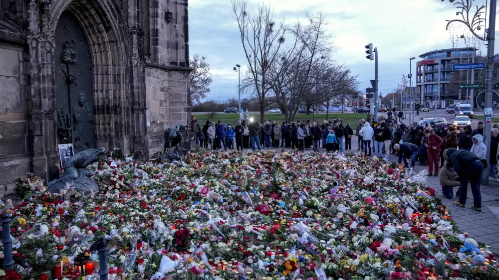 People lay flowers and lit candles in front of the Johannis church close to the Christmas market, where a car drove into a crowd on Friday evening, in Magdeburg, Germany, Sunday, Dec. 22, 2024. (AP Photo/Ebrahim Noroozi)