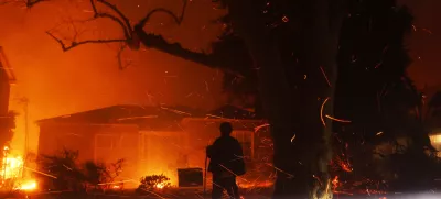 FILE - A person tries to hose down embers from the Palisades Fire in the Pacific Palisades neighborhood of Los Angeles, Jan. 7, 2025. (AP Photo/Etienne Laurent, File)