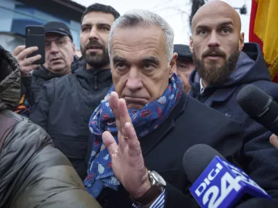 Calin Georgescu, center, an independent candidate for president who won the first round of presidential elections, makes his way, surrounded by media, to a closed voting station after Romania's Constitutional Court annulled the first round of presidential elections, in Mogosoaia, Romania, Sunday, Dec. 8, 2024. (AP Photo/Vadim Ghirda)