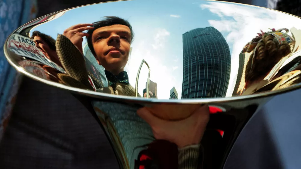 A cast member looks at his reflection in a trombone as he fixes his hair while the cast of Broadway show The Music Man pose for photos across the street from the Winter Garden in the Manhattan borough of New York City, New York, U.S., February 8, 2022. REUTERS/Carlo Allegri   TPX IMAGES OF THE DAY